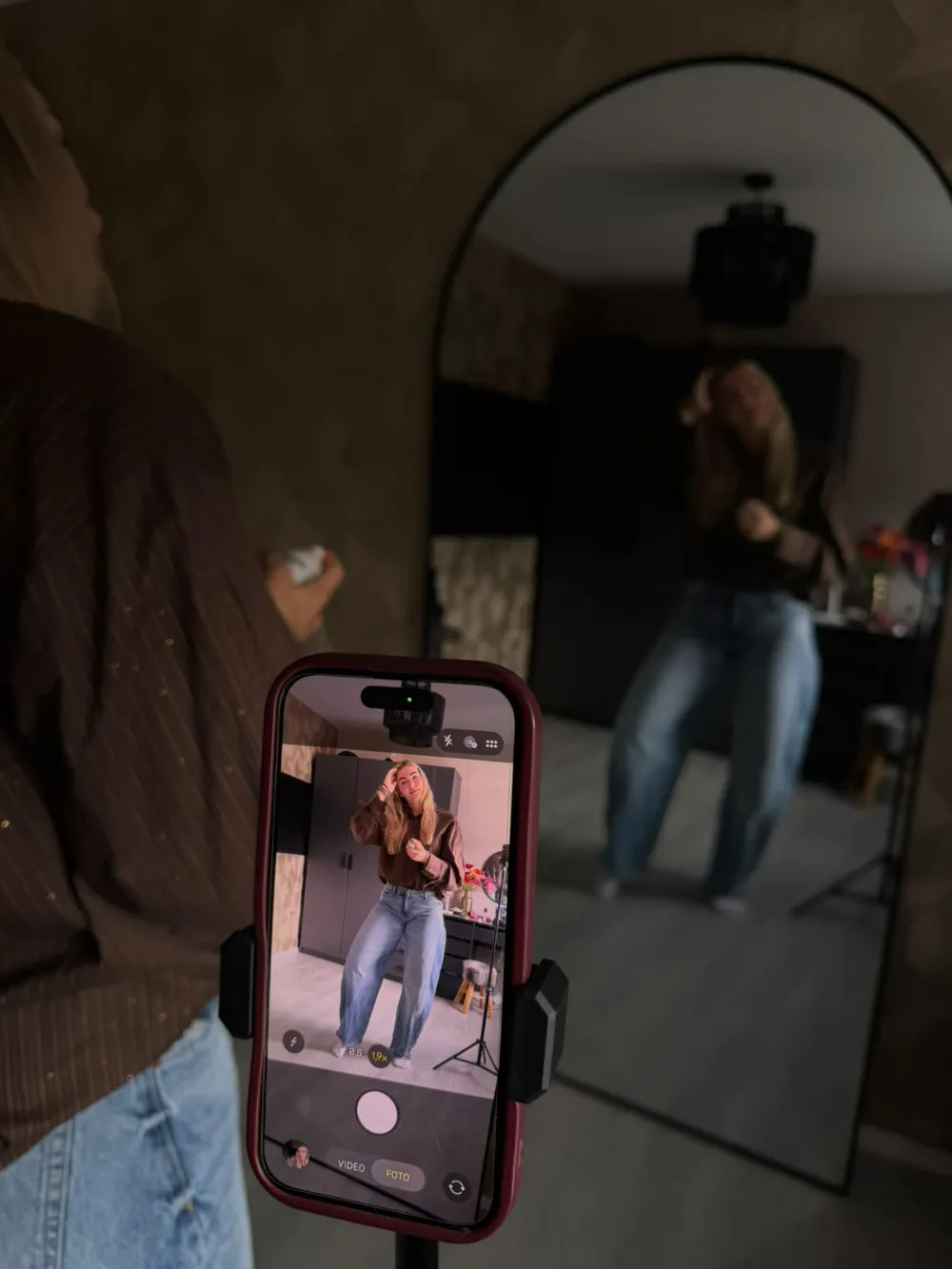 Joy filmt zichzelf met haar telefoon op een statief voor de spiegel